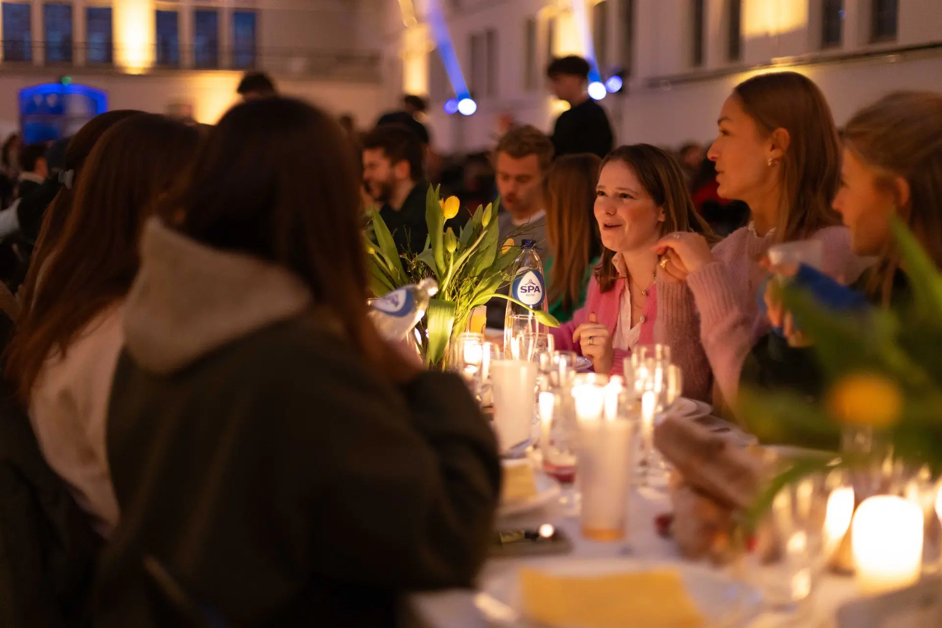 Lachende gasten rond een tafel met kaarslicht